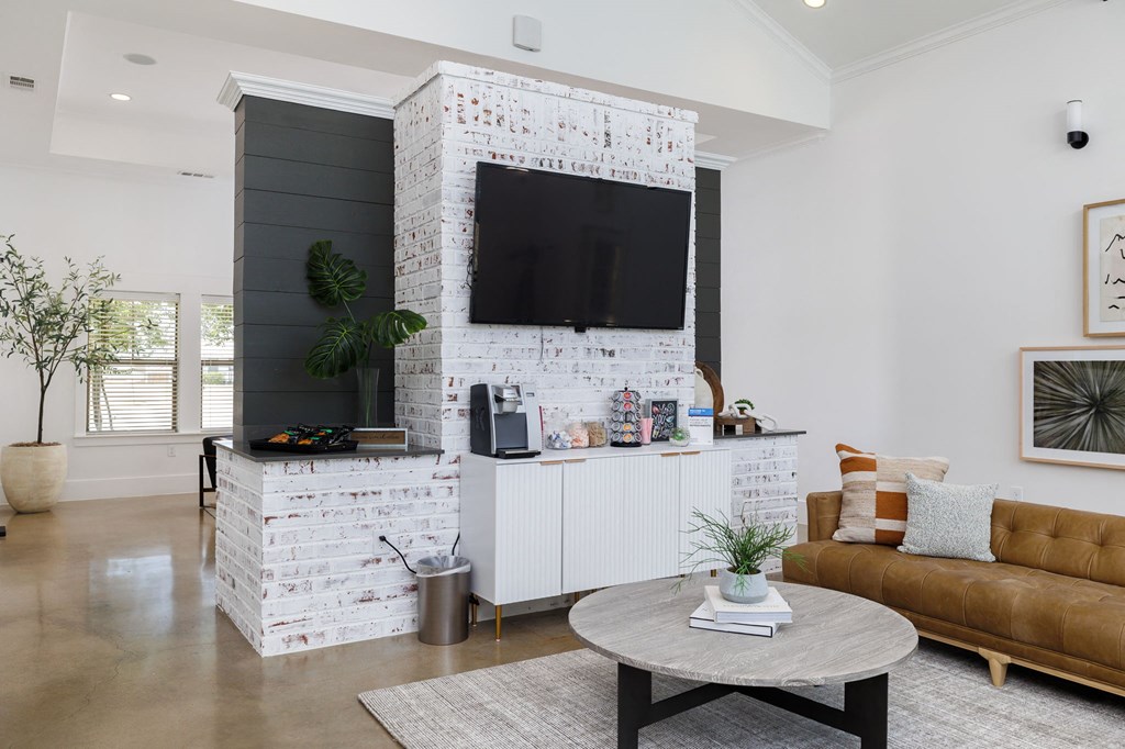 a living room with a white brick accent wall and a large flat screen tv on top of