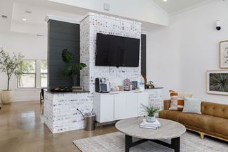 a living room with a white brick accent wall and a large flat screen tv on top of - Photo Gallery