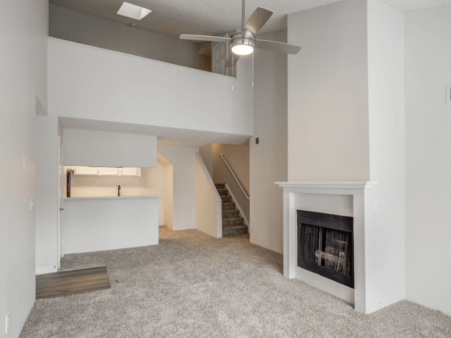 an empty living room with a fireplace and a ceiling fan