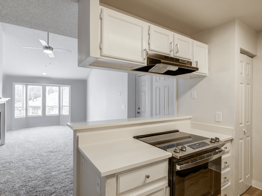 an empty kitchen with white cabinets and an oven and stove