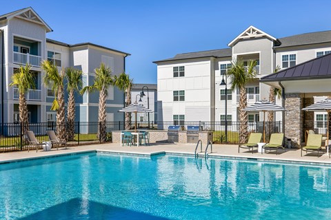 A swimming pool in front of a building with palm trees.