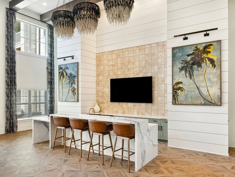 A modern kitchen with a bar area and a painting of a palm tree on the wall.