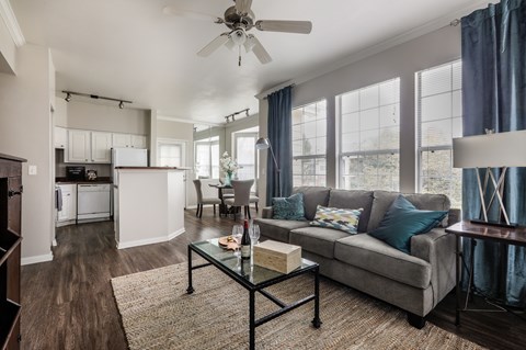 A living room with a grey couch and a glass coffee table.