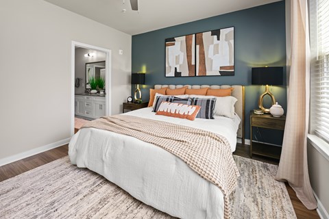 A bedroom with a large bed and a painting on the wall.
