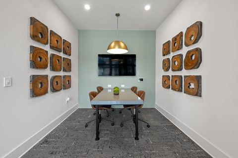 A conference room with a table, chairs, and a wall of wood slices.