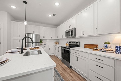 a large kitchen with white cabinets and black appliances