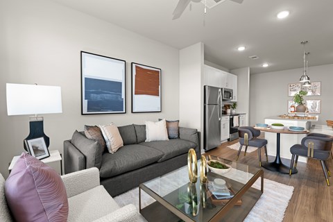 A modern living room with a grey couch and a glass coffee table.
