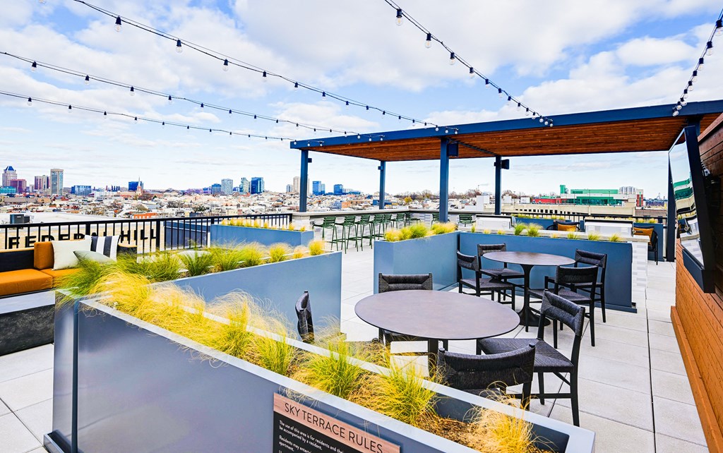 A rooftop patio with tables and chairs overlooking a city skyline.