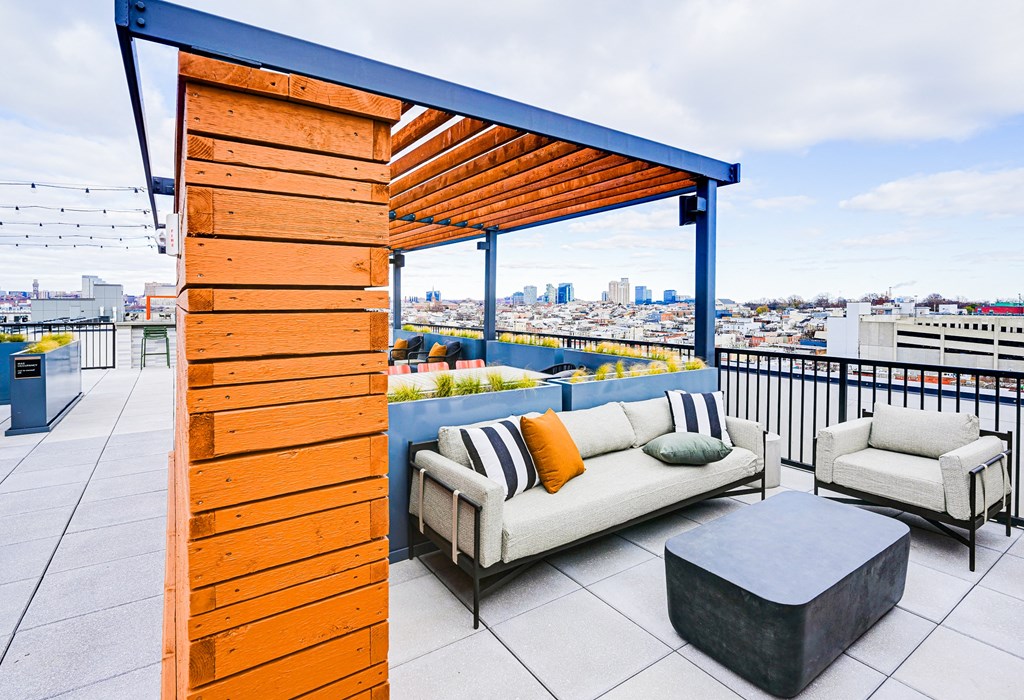 A wooden structure with a white couch and a black ottoman on a patio.