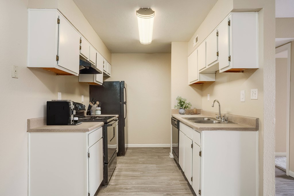 A kitchen with white cabinets and a black refrigerator.