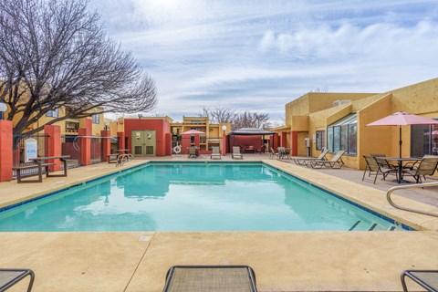 A large outdoor swimming pool surrounded by lounge chairs and umbrellas.