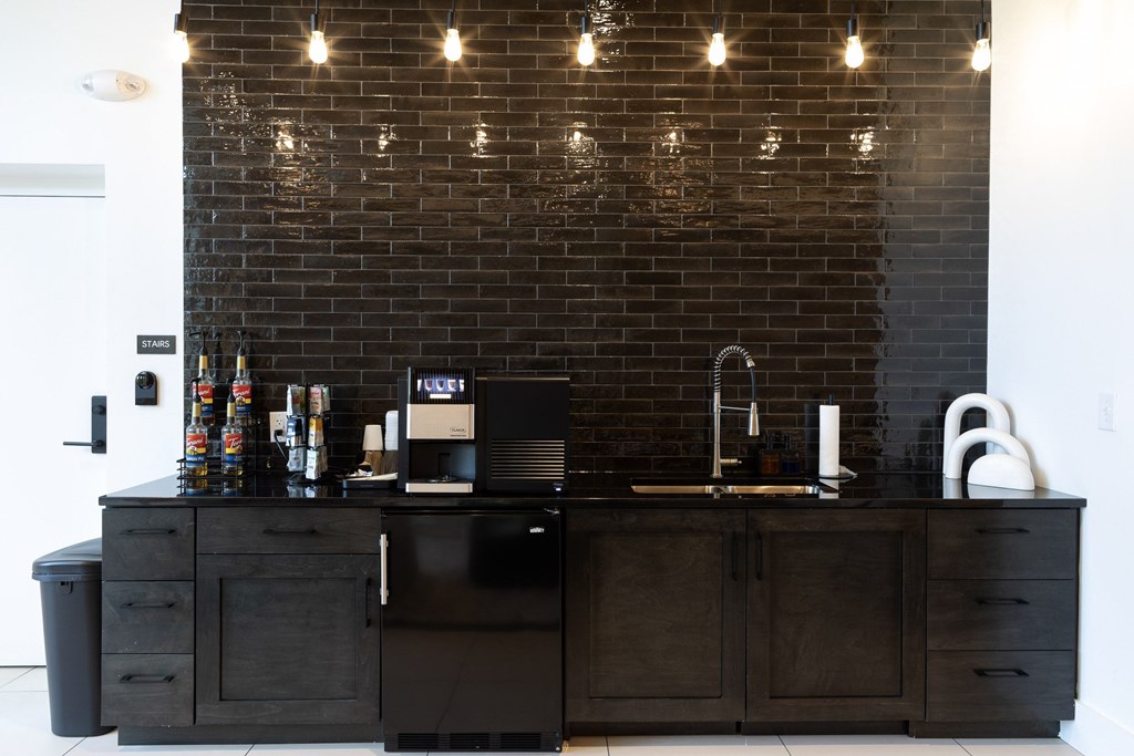 A black kitchen with a brick wall and lights above it.