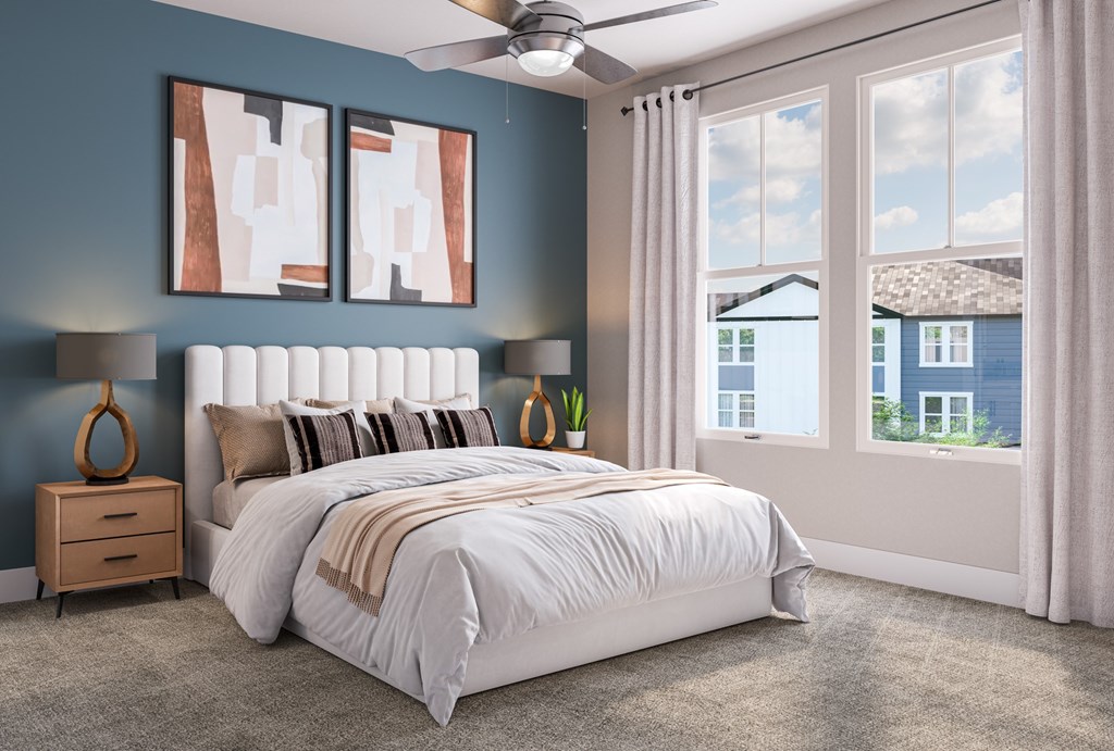 A bedroom with a large bed, a ceiling fan, and a view of a house through the window at Easton at Mountain Island apartments in Charlotte, NC.