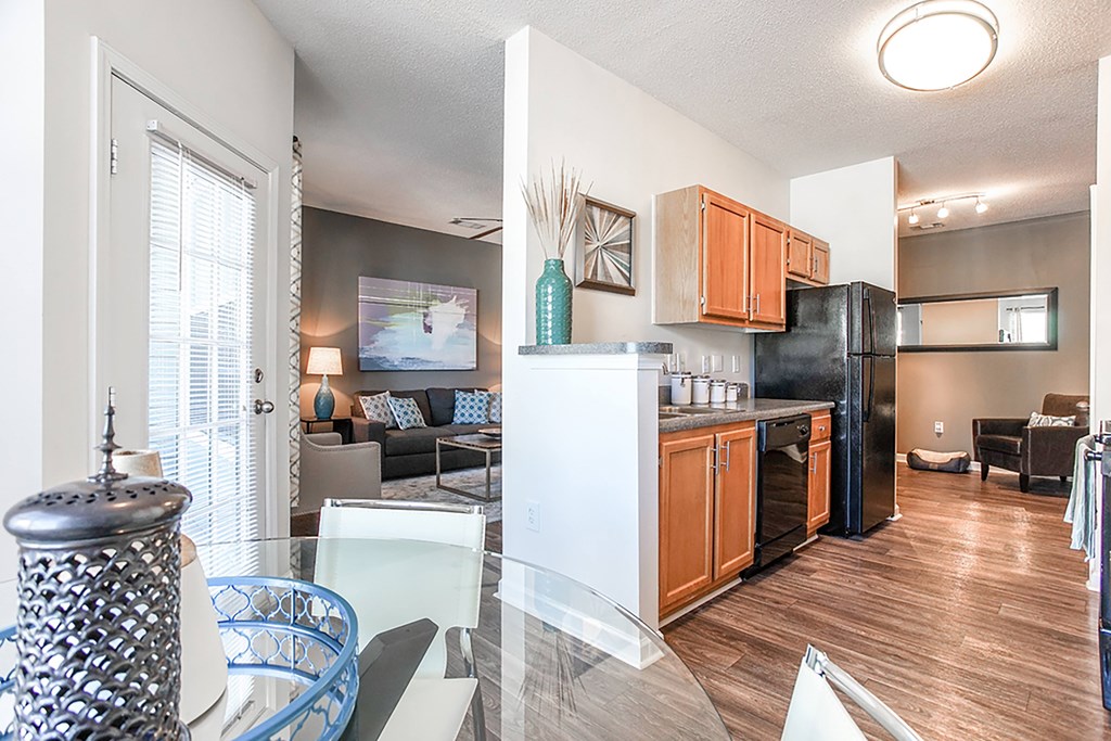 A kitchen with a black fridge and wooden cabinets.