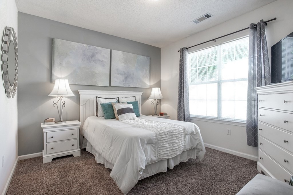 A bedroom with a large bed and two lamps.