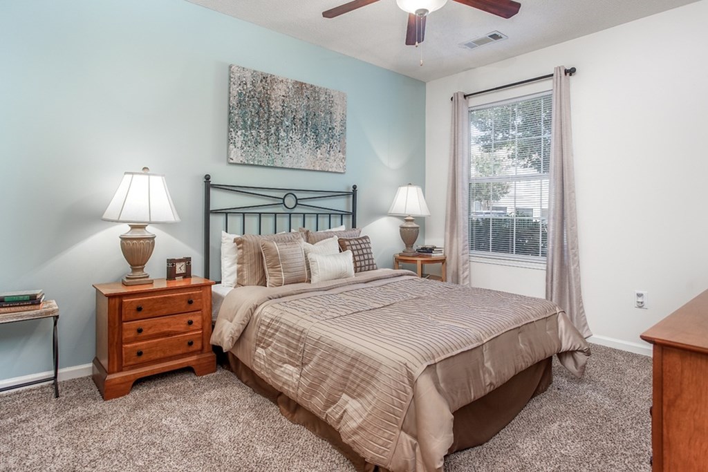 A bedroom with a bed, nightstands, and a ceiling fan.