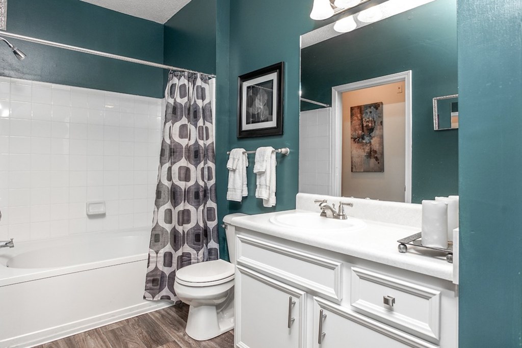 A white toilet sits in a bathroom with a blue wall.