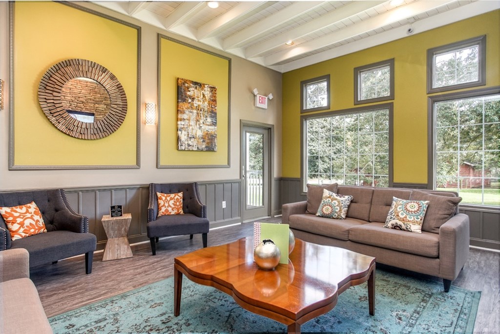 A living room with a grey couch, a brown coffee table, and a woven basket on the wall.