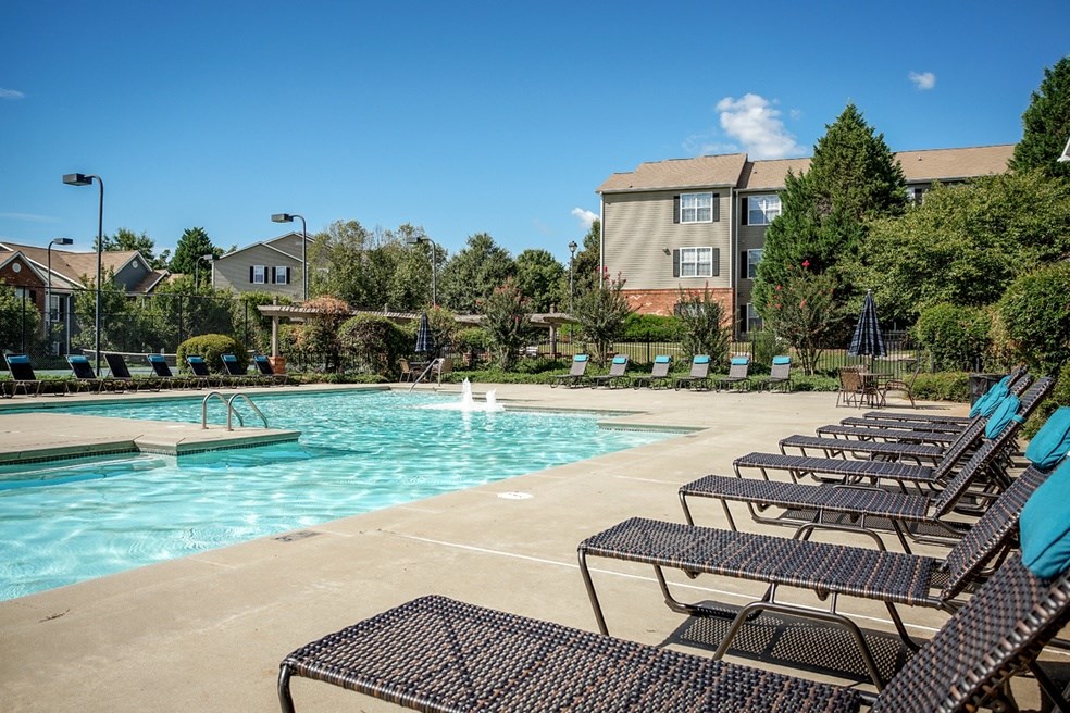 A pool with chairs around it and a building in the background.