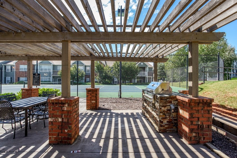 A tennis court is visible through a wooden pergola.