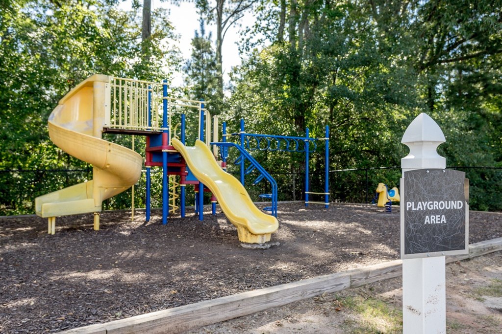 A playground area with a yellow slide and a sign.