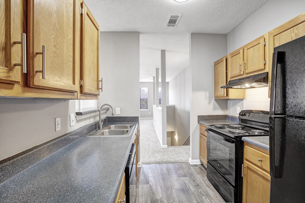 A kitchen with black appliances and wooden cabinets.