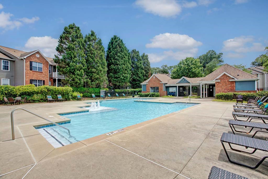 A swimming pool surrounded by lounge chairs and trees.