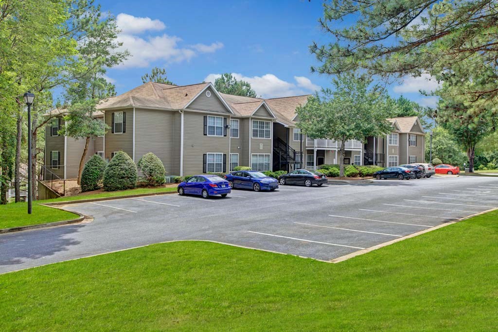 A parking lot in front of a building with cars parked.