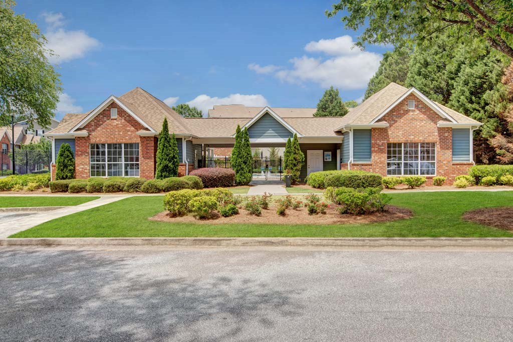 A house with a brick facade and a green lawn in front.