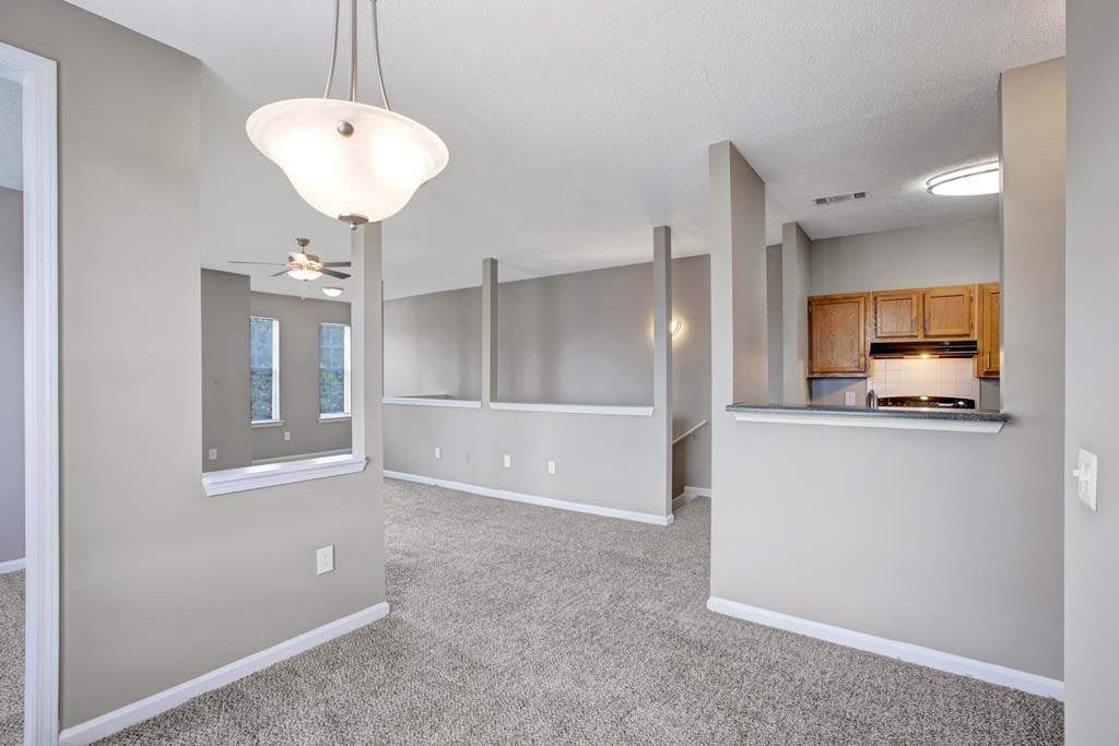 A spacious living room with a kitchenette in the background.