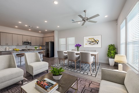 a living room and kitchen with a table and chairs and a ceiling fan