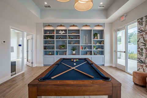 a pool table in a living room with a bookshelf