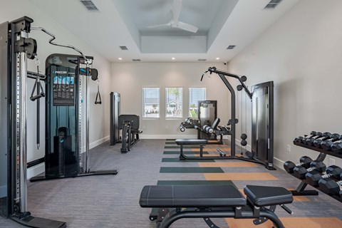 a fitness room with weights and cardio equipment and a window