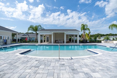 a large swimming pool with a house in the background