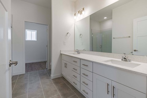 a white bathroom with two sinks and a large mirror