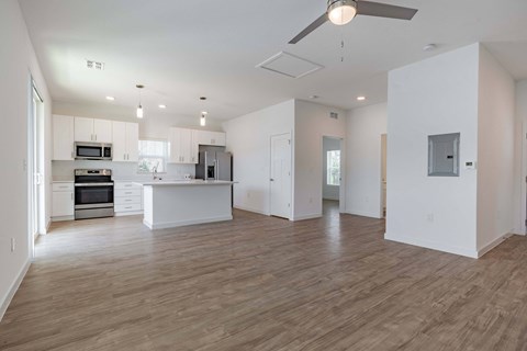 an empty kitchen and living room with a ceiling fan