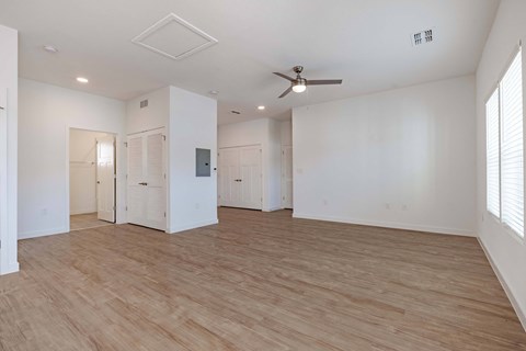 an empty living room with white walls and a ceiling fan