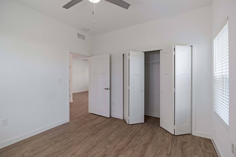 a bedroom with three closets and a ceiling fan