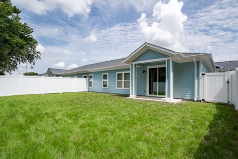 a blue house with a yard and a white fence