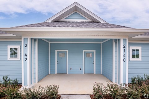 a blue house with two doors and a porch