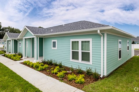 a row of blue houses with a sidewalk in front of them