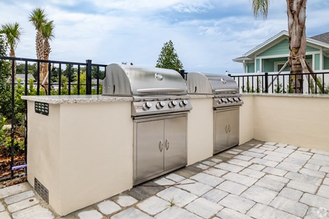 two stainless steel barbecue grills on a patio in front of a house