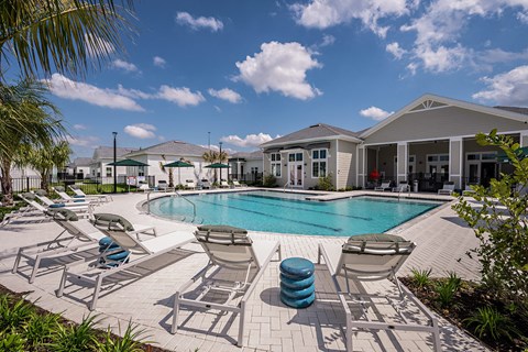our resort style swimming pool is surrounded by lounge chairs and houses