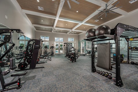 a gym with weights and other equipment in a building with windows