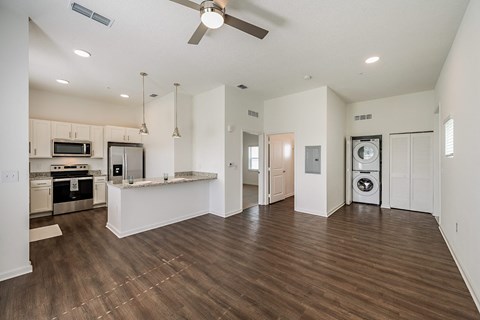 an empty living room with a kitchen and a washer and dryer