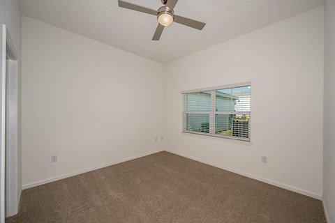 an empty living room with a ceiling fan and a window
