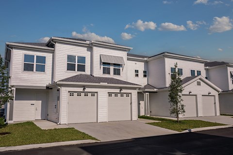 a white house with white garage doors and a sidewalk