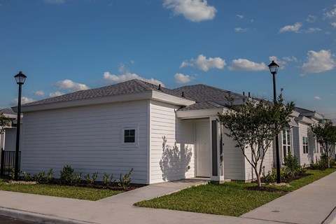 a white house with a sidewalk and street lamps