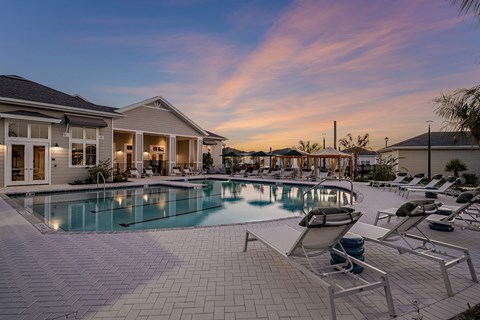 a large swimming pool with lounge chairs in front of a house