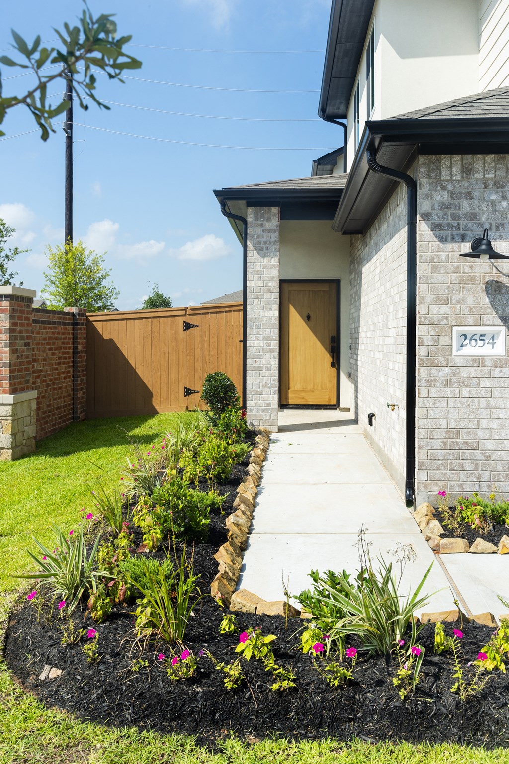 the front yard of a house with a walkway and flower garden